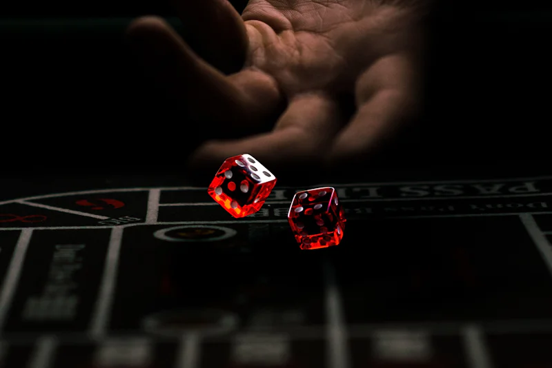 Hand releasing two red dice over a casino craps table