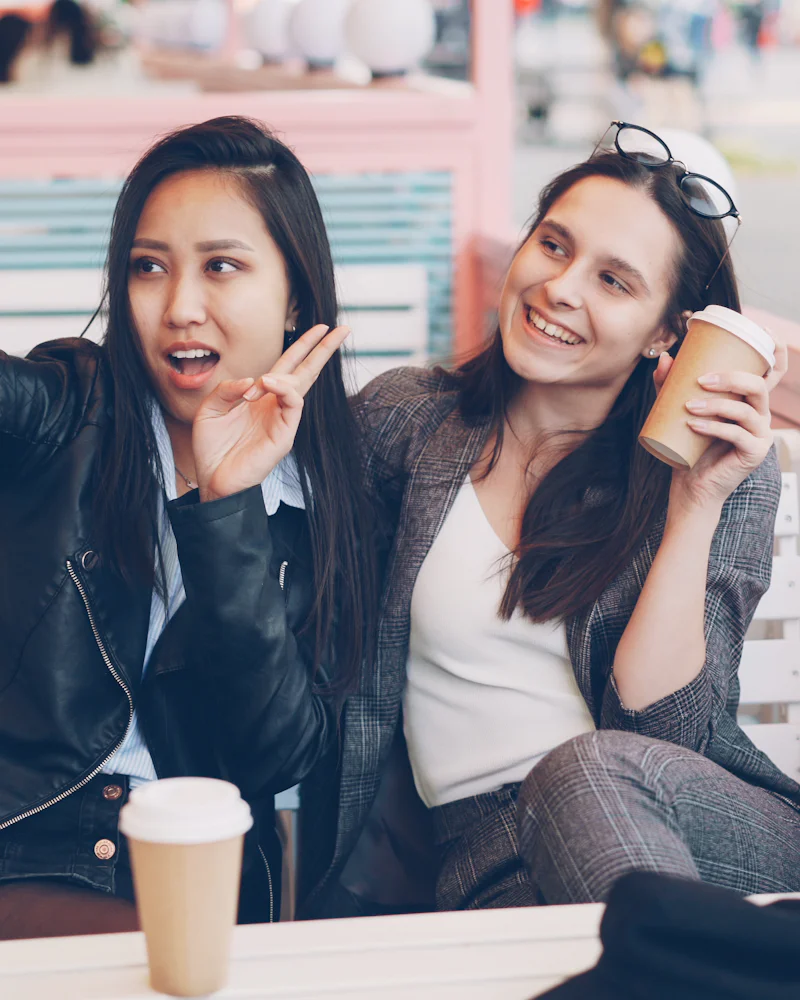 Two smiling young women taking a selfie together at a cafe
