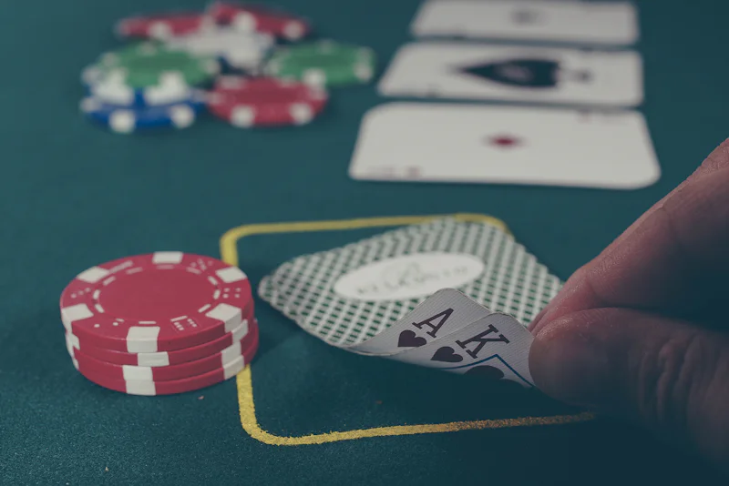 Player lifting the corner of an ace and king on a green poker table