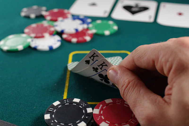Poker player peeking at a pair of kings beside red, green and blue chips
